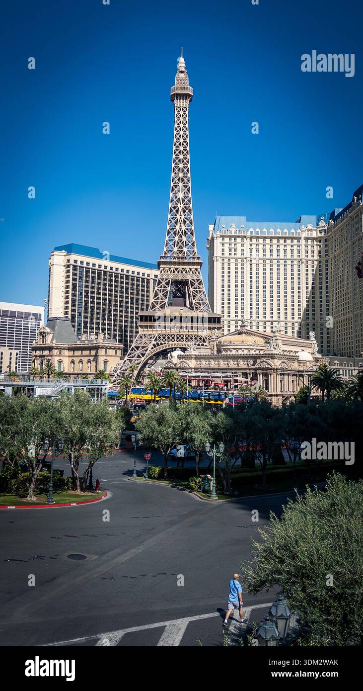 Nachbildung des Eiffelturms im Halbmaßstab im Paris Las Vegas Hotel unter blauem Himmel, Palmen und umliegenden Kasinotürmen an sonnigen Tagen - Smartphone-aufgenommenes Stockfoto