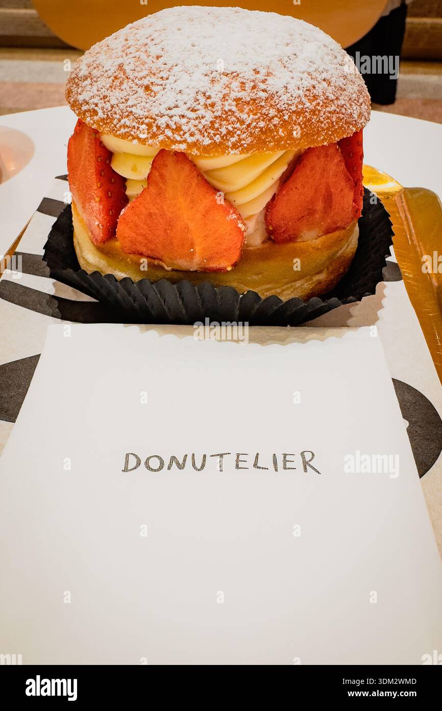 Dekadente Erdbeercreme Gourmet-Donut von Donutelier, garniert mit Puderzucker, frischen Erdbeeren und Chantilly-Creme-Füllung auf schwarzem Liner wi - Smartphone-aufgenommenes Stockfoto