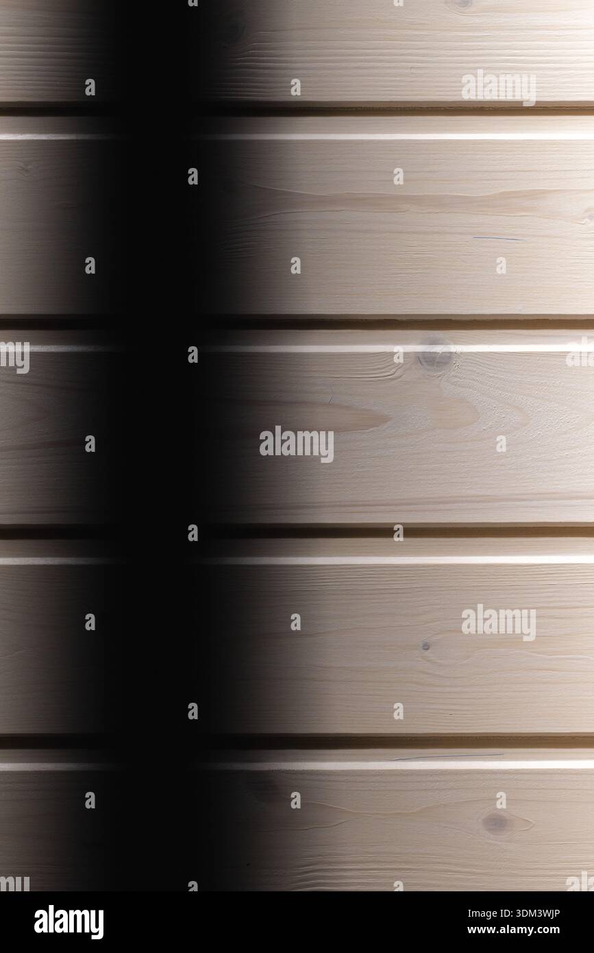 Glatte Holzdielen bilden eine horizontale Wandstruktur, die in sanftes Licht getaucht ist und einen dramatischen vertikalen Schatten erzeugt. Ein vielseitiger Hintergrund für Design, Stockfoto