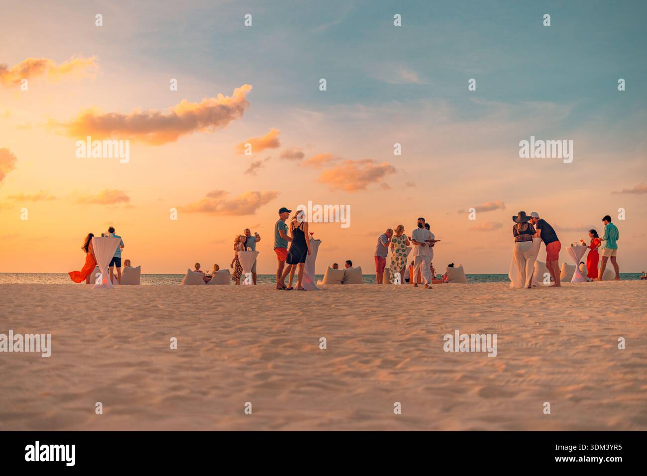 Sunset Beach Party Leute unterhalten sich und genießen Sonnenuntergangsstimmung. Strandurlaub Entspannung tropischer Ozean Sommer soziale Szene Luxusreisen Stockfoto