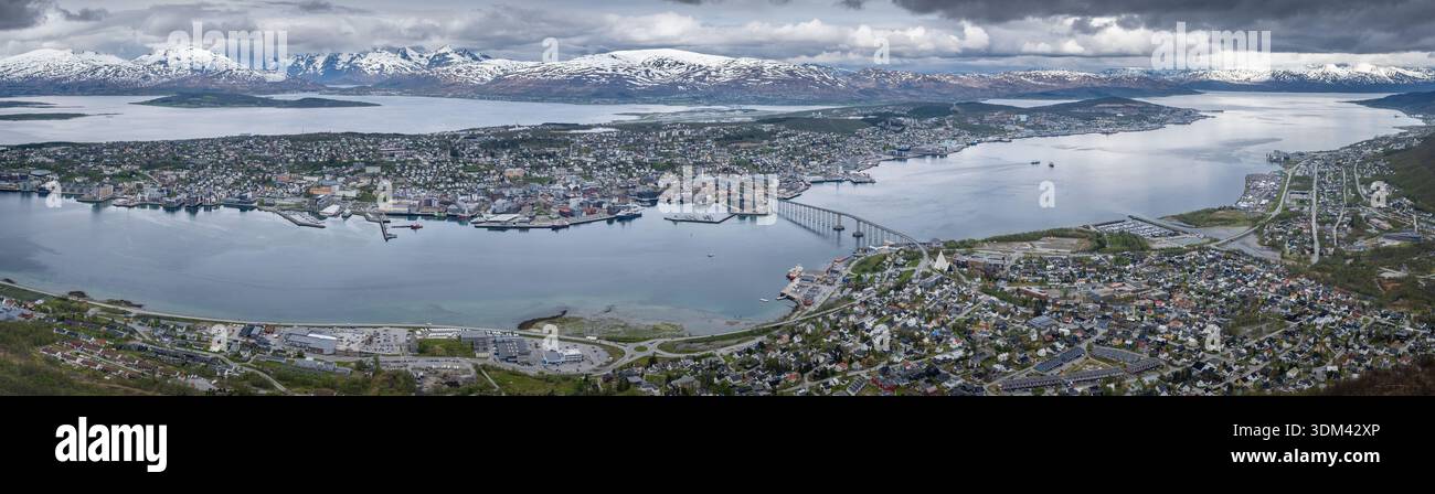 Panoramablick vom Storsteinen aus aus der Luft zeigt die Stadt Tromsø, die sich entlang des Fjords erstreckt und von schneebedeckten Bergen eingerahmt wird Stockfoto