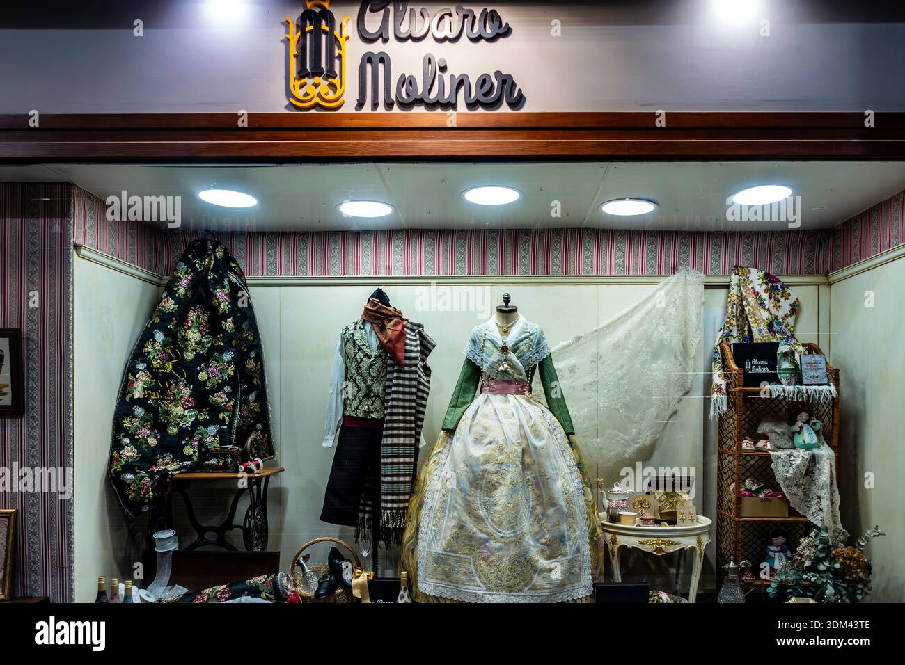 Traditionelle Fallera-Kleider im Stil des 18. Jahrhunderts und kunstvoll verzierte Seidenstoffe werden in der Ladenfront des Álvaro Moliner, einer historischen Boutique in Valencia, ausgestellt. Stockfoto