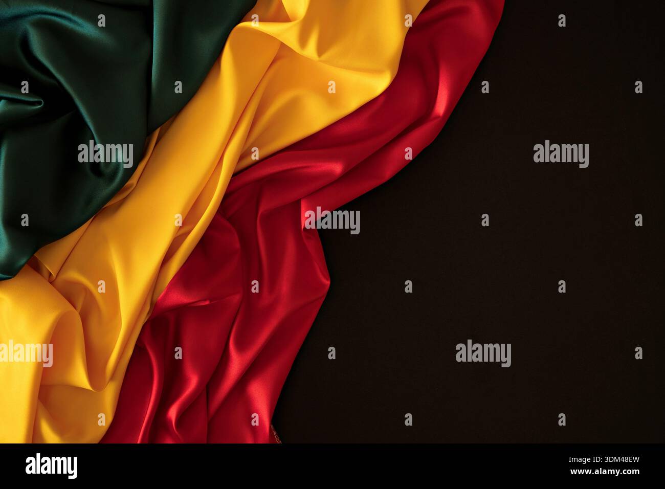 Hintergrund für schwarzen Monat. Rote, gelbe, grüne Farben Vorhänge, Seidenfahne auf schwarzem Hintergrund. Draufsicht Stockfoto