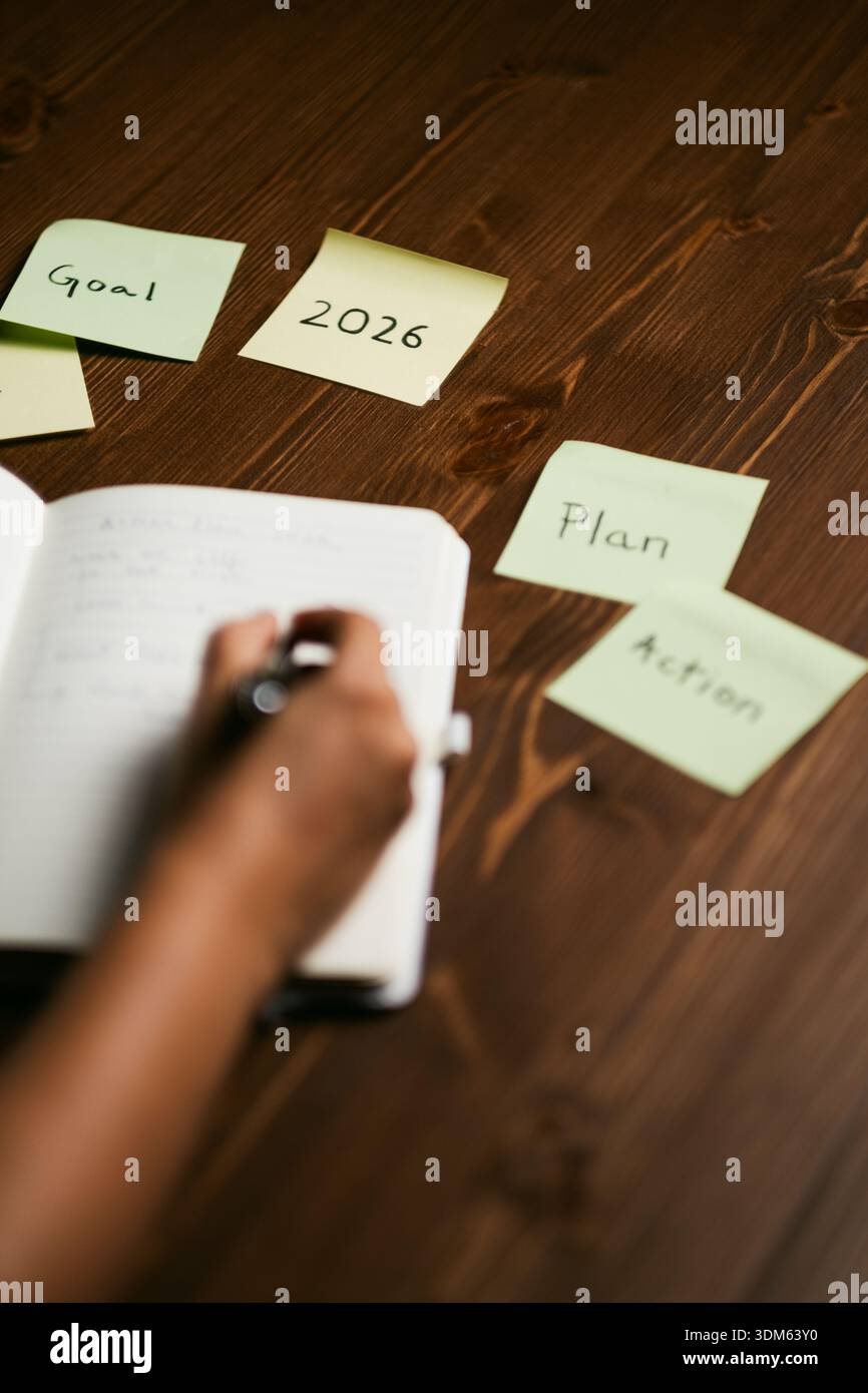 Frau schreibt Ziele und Pläne im Journal mit Erinnerungen an Produktivität und Erfolg Stockfoto
