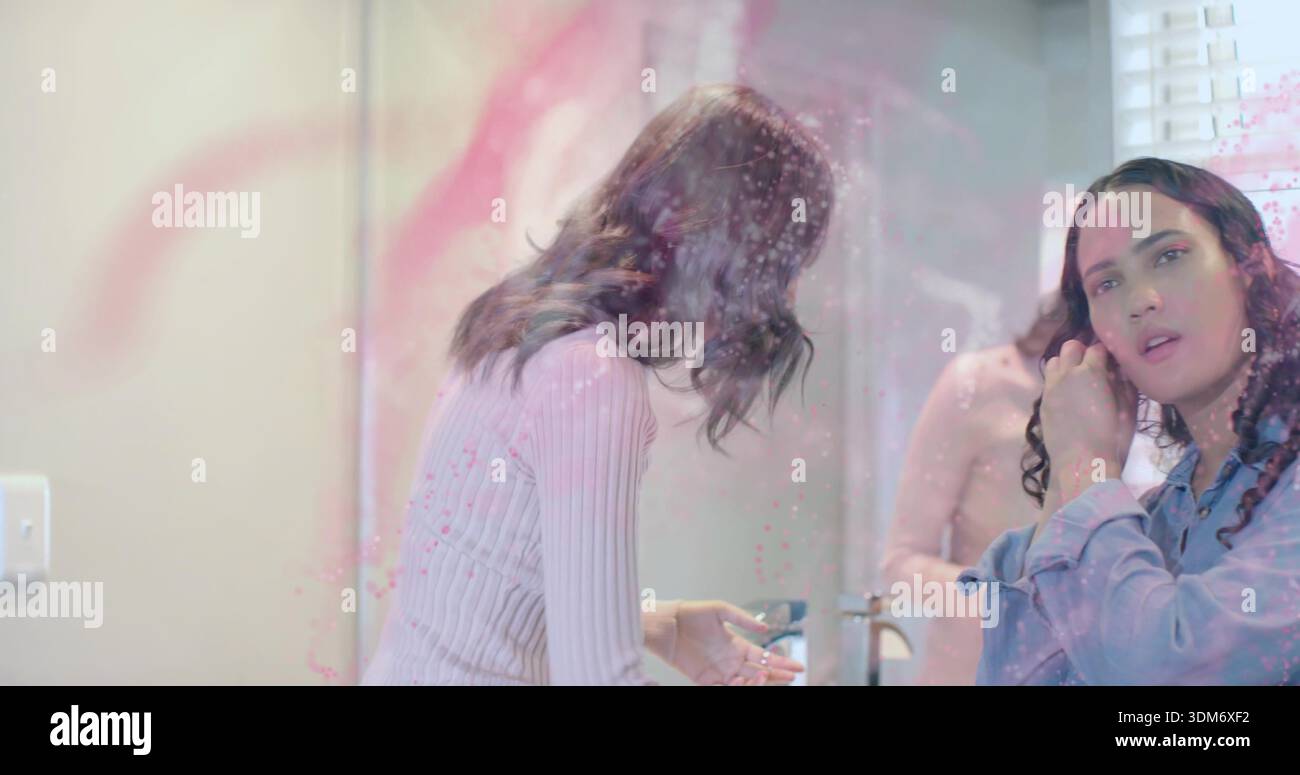 Lehnende Frau in rosa, die Seife hält, Frau in Blau, die Haare am Waschbecken im Badezimmer anpasst, Spiegel Stockfoto