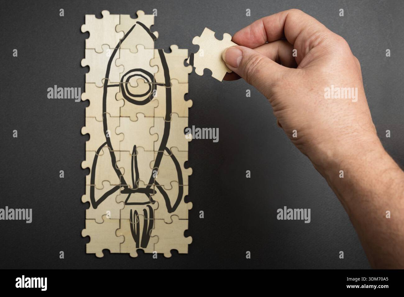 Geschäftskonzept, das ein Holzraketenpuzzle mit einem fehlenden Stück zeigt, das von einer Hand gehalten wird. Symbolisches Bild für Strategieentwicklung, Problemlösung Stockfoto