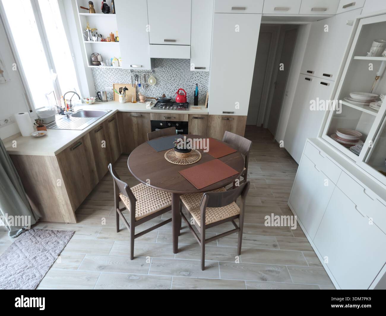 Wohnzimmerdesign kombiniert mit Küche, mit weißem Sideboard. Holzmöbel mit Buchenfurnier, Tisch und Stühlen. Skandinavischer Stil Stockfoto