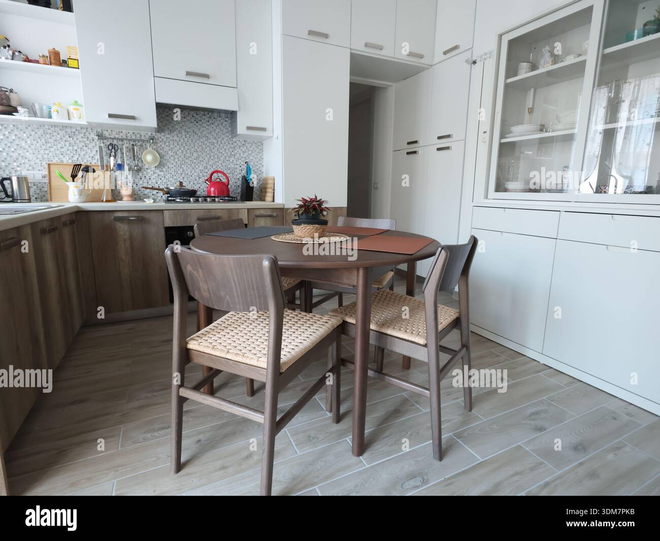 Wohnzimmerdesign kombiniert mit Küche, mit weißem Sideboard. Holzmöbel mit Buchenfurnier, Tisch und Stühlen. Skandinavischer Stil Stockfoto