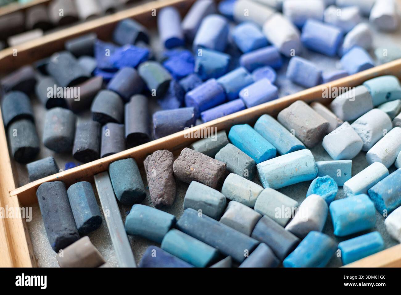 Blaues Weichpastellkreidesammlung im Holzkoffer. Kunstwerke bieten Stauraum für Pastellmalerei und Zeichenwerkzeuge. Kunst kreativ, Hobby, Malkonzept Stockfoto