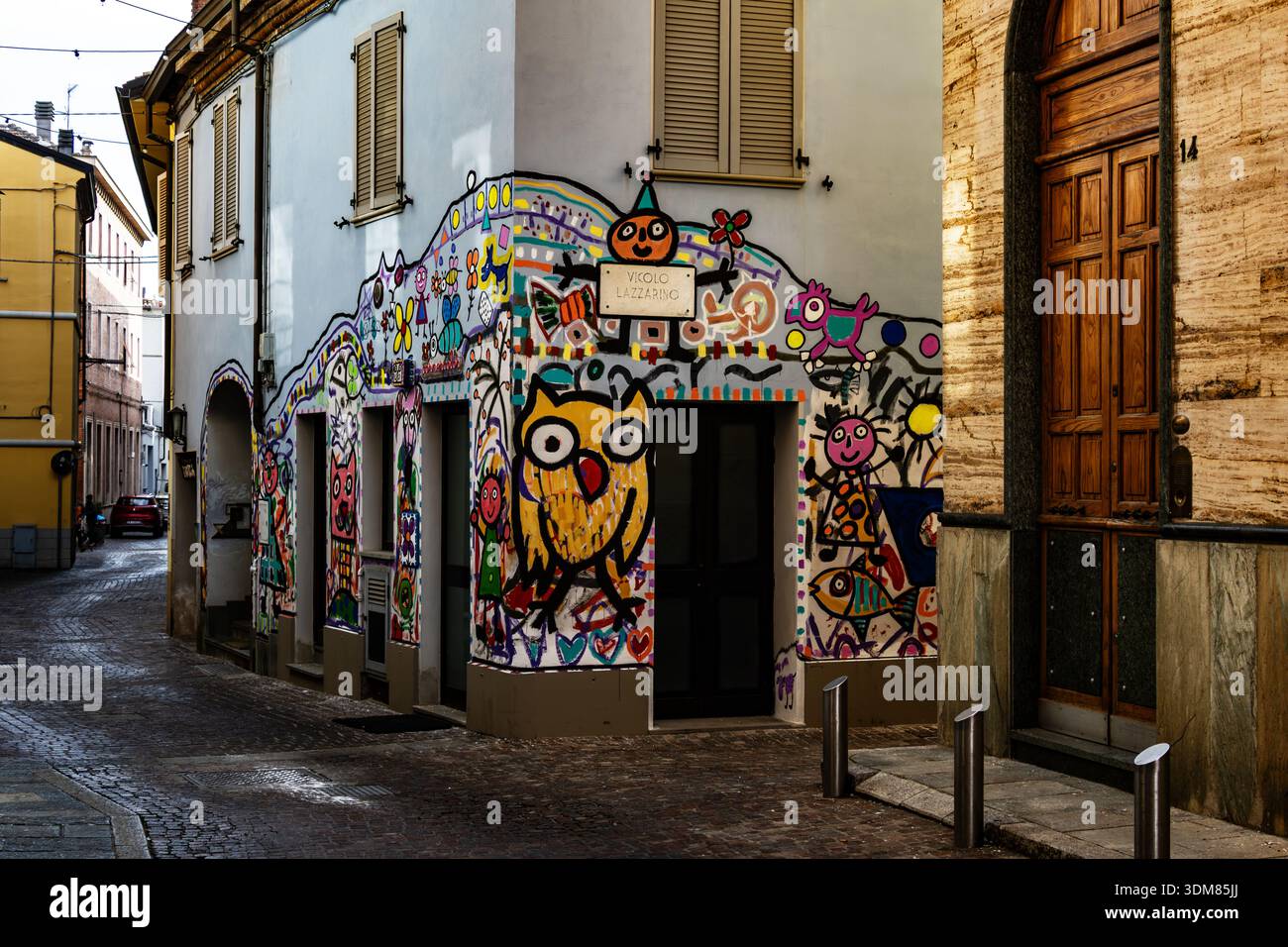 Ein lebhaftes Straßengemälde mit einer großen gelben Eule und skurrilen Schriftzeichen ziert die Ecke eines italienischen Steingebäudes Stockfoto