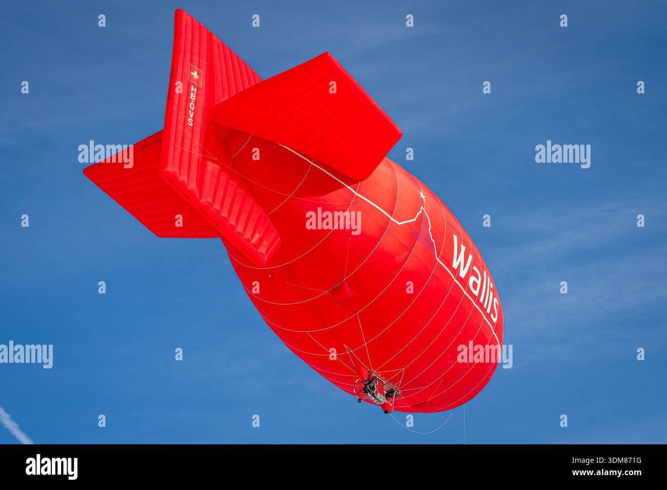 Chateau d'oex, Kanton Waadt, Schweiz - 1. Februar 2026: Roter Heißluftballon Wallis Luftschiff fliegt über blauem Himmel in der Schweiz Winter. Stockfoto