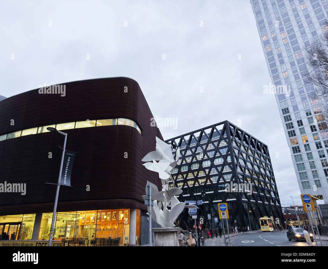 Manchester, Großbritannien - 21. Januar 2026: Modernes Stadtmuseum mit einem runden roten Gebäude, einem Glasbüro und einer weißen Skulptur Stockfoto