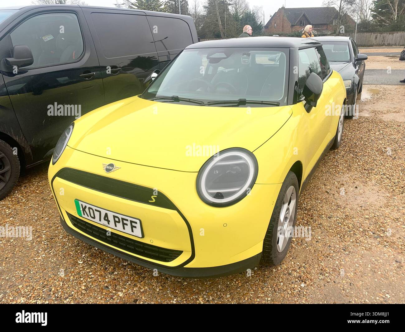 Gelbes und schwarzes ORA Elektroauto parkt in einem britischen Supermarkt Parkplatz Mini cooper S in der Nähe von Trolleys und anderen Fahrzeugen im Hintergrund - Smartphone-aufgenommenes Stockfoto