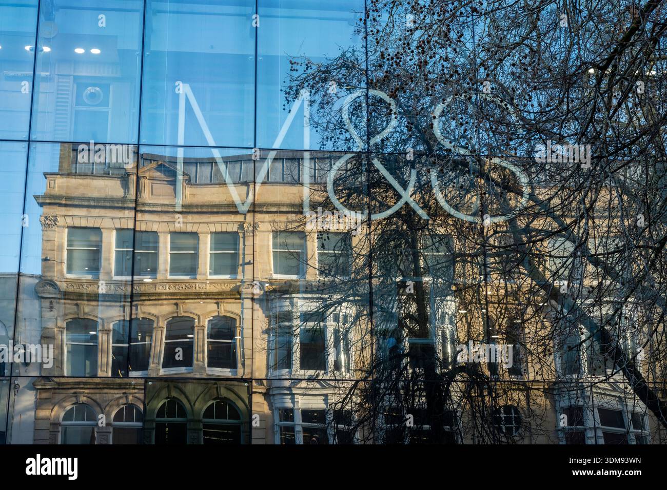 Große Marken und Spencer-Logo spiegeln sich in den Glasfenstern eines Büroblocks im Stadtzentrum von Cardiff, Wales, Großbritannien Stockfoto