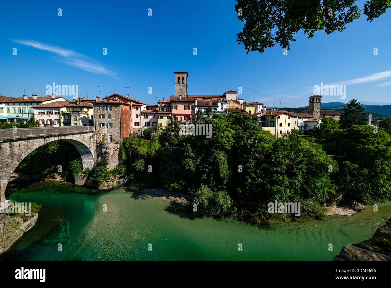 Die Steinbrücke Teufelsbrücke über den türkisfarbenen Fluss Natisone mit der Kirche San Francesco auf einer Klippe in Cividale del Friuli. Stockfoto