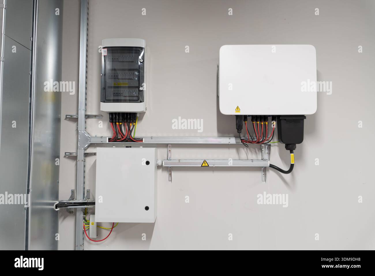 Solarwechselrichter, der neben zwei Schaltschränken installiert ist und Geräte für die Energiemanagement und -Verteilung in Photovoltaikanlagen zeigt. Stockfoto