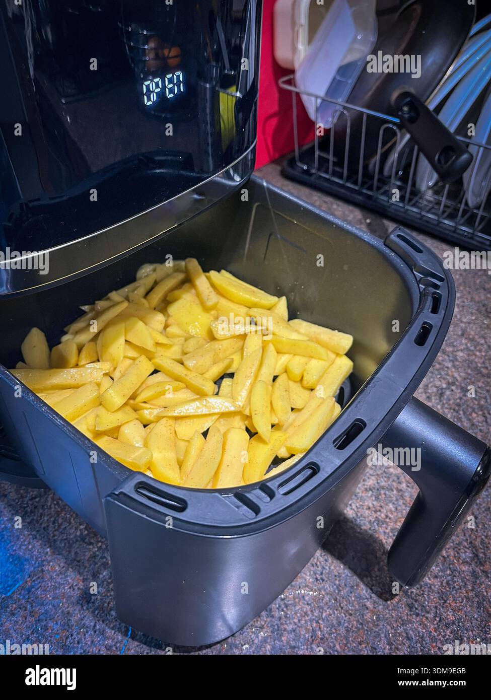 Rohe Kartoffeln im Korb der Luftfritteuse bereit zum Kochen - Smartphone-aufgenommenes Stockfoto