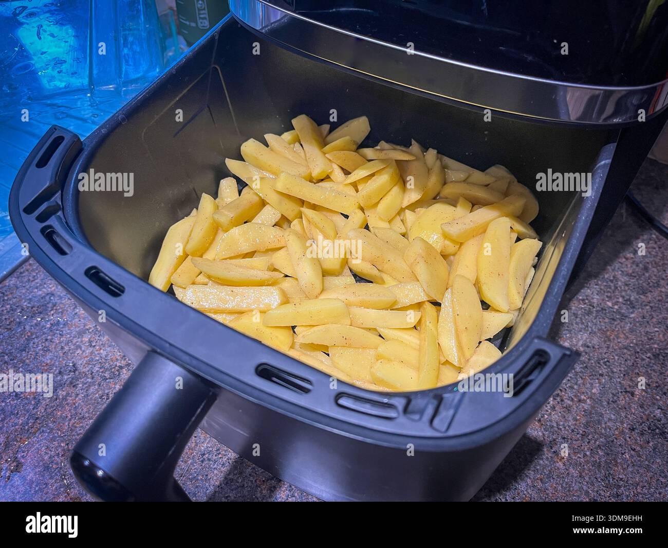 Rohe Kartoffeln im Korb der Luftfritteuse bereit zum Kochen - Smartphone-aufgenommenes Stockfoto