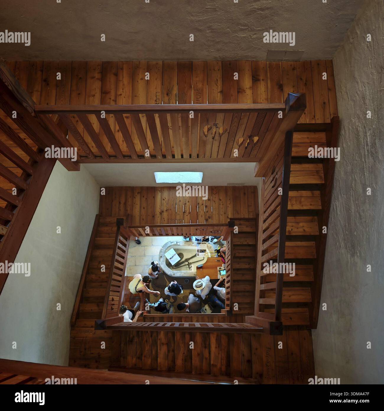 Holztreppe mit Blick auf eine Gruppe von Menschen, die sich im Erdgeschoss in Piran, Slowenien, versammelt haben Stockfoto