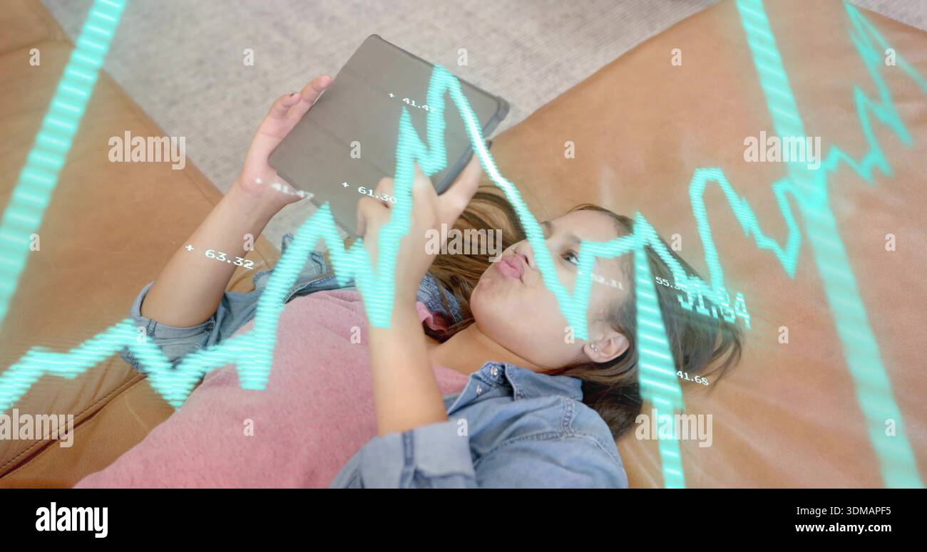 Liegender Teenager mit rosafarbenem T-Shirt, Jeansjacke, Tablette oben auf einem braunen Sofa mit türkisfarbenem Überzug Stockfoto