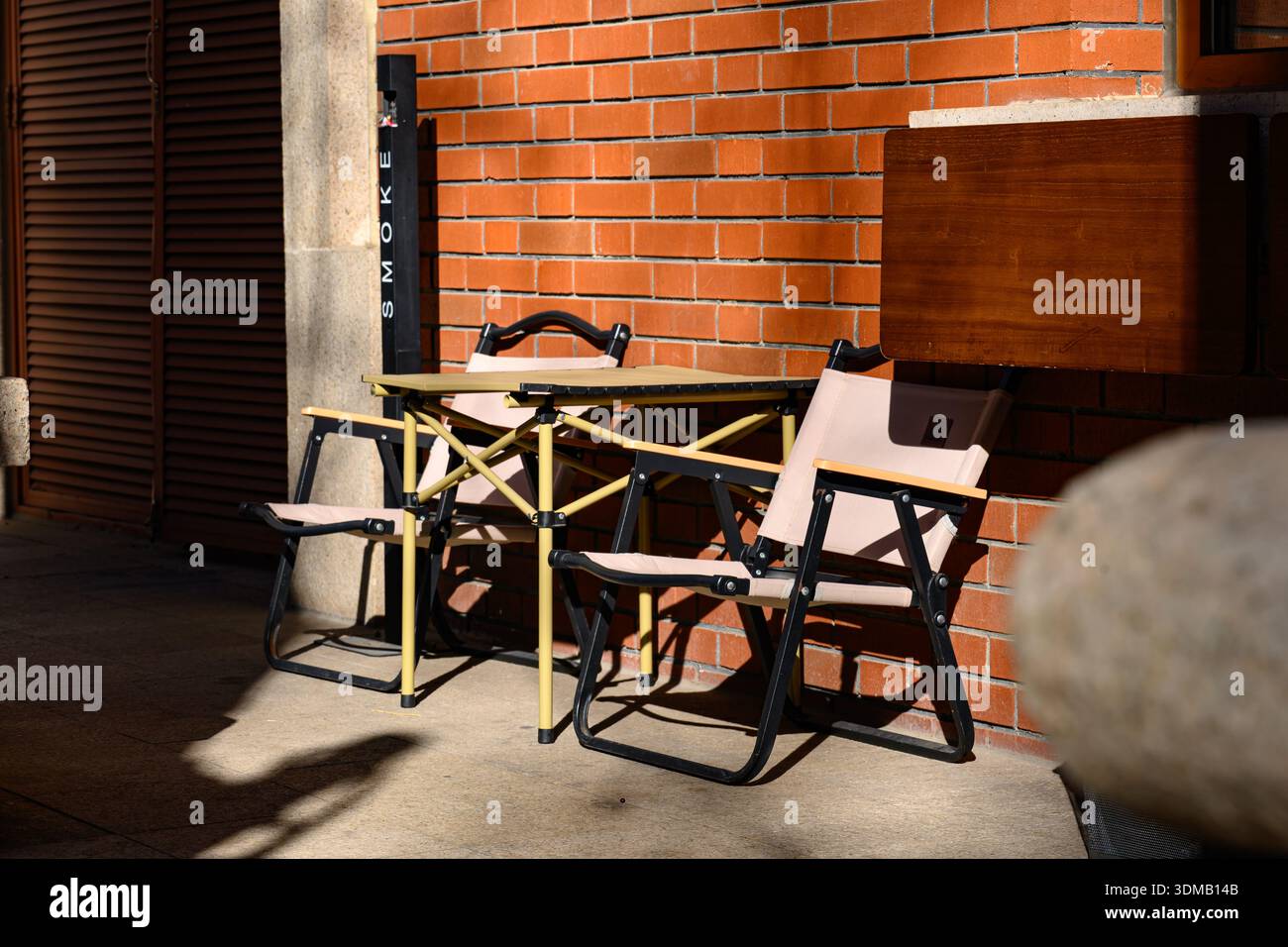 Stühle und Tisch im Freien vor der sonnendurchfluteten Wand Stockfoto