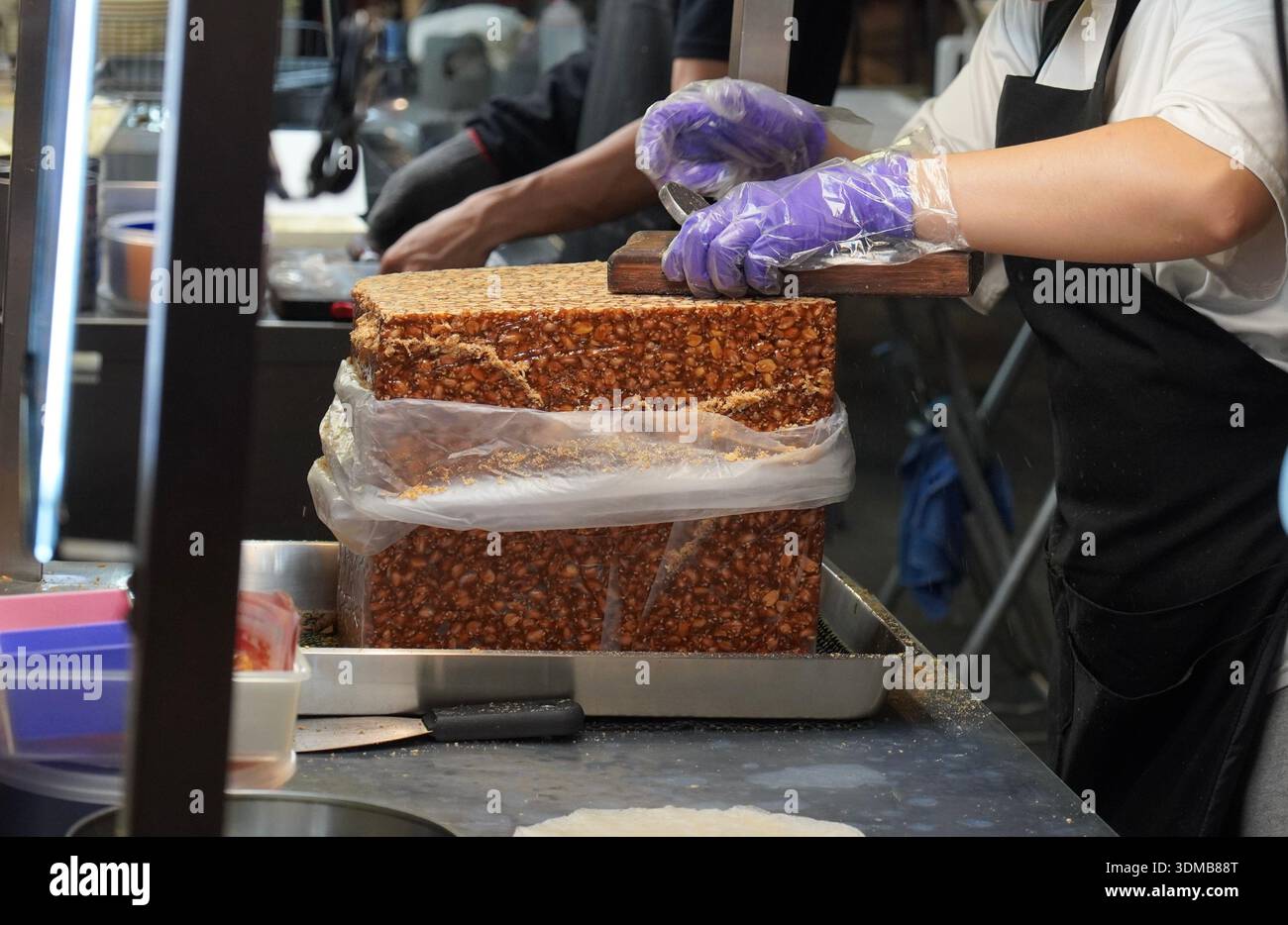 Ein Street Food-Händler rasiert die Erdnuss für das beliebte Gericht Taro-Eis-Pfannkuchen mit Erdnuss. Stockfoto