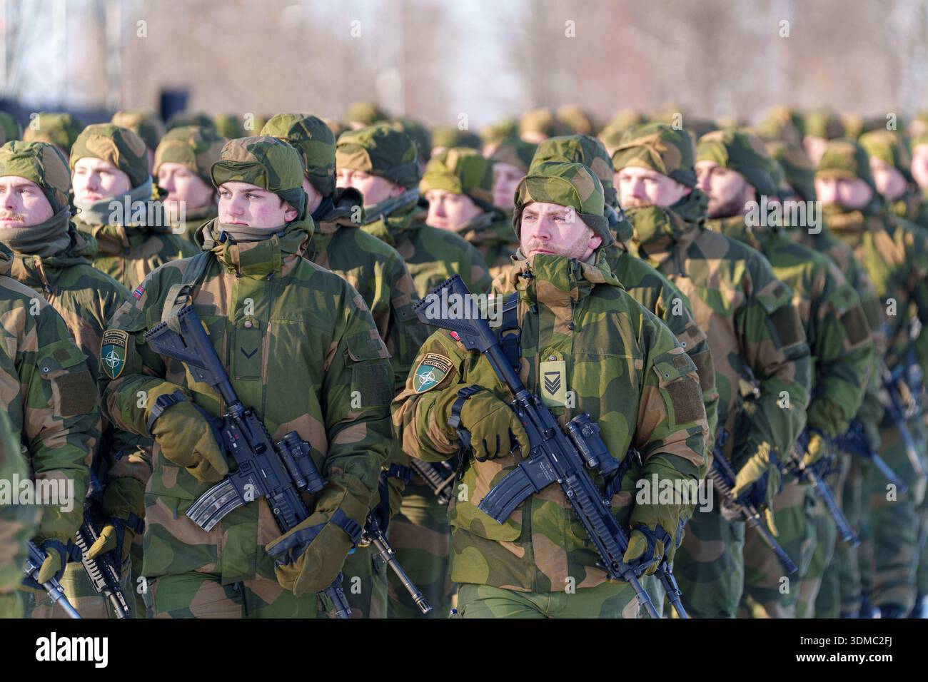 Soldaten in Tarnuniformen mit Norwegerflagge und NATO-Patches mit Gewehren im Winter. Stockfoto
