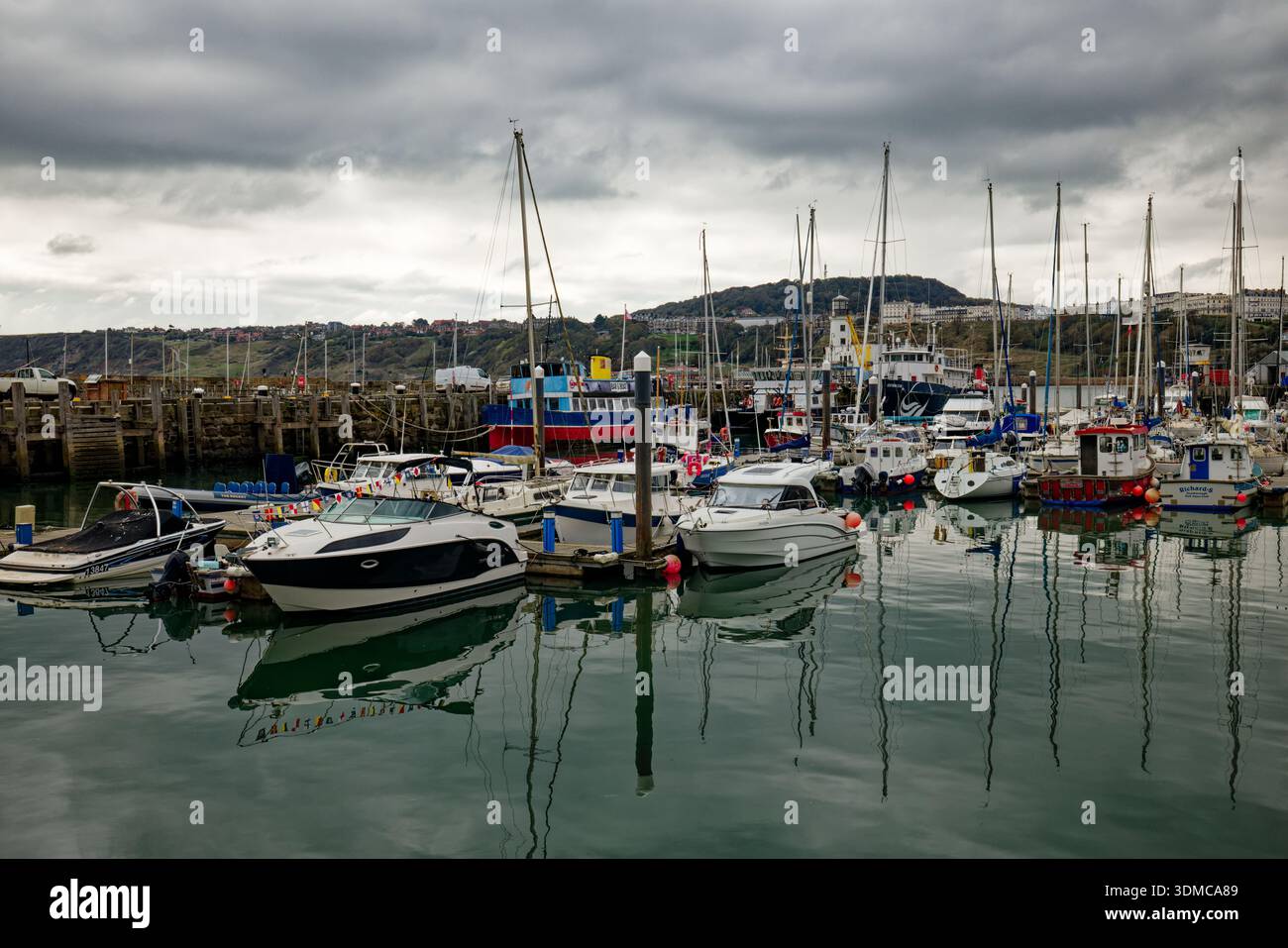 Ein Wald von Yachtmasten von Booten, die im Hafen mit dem Resort Scarborough an der Küste im Hintergrund, North Yorkshire, England, vertäut sind. Stockfoto