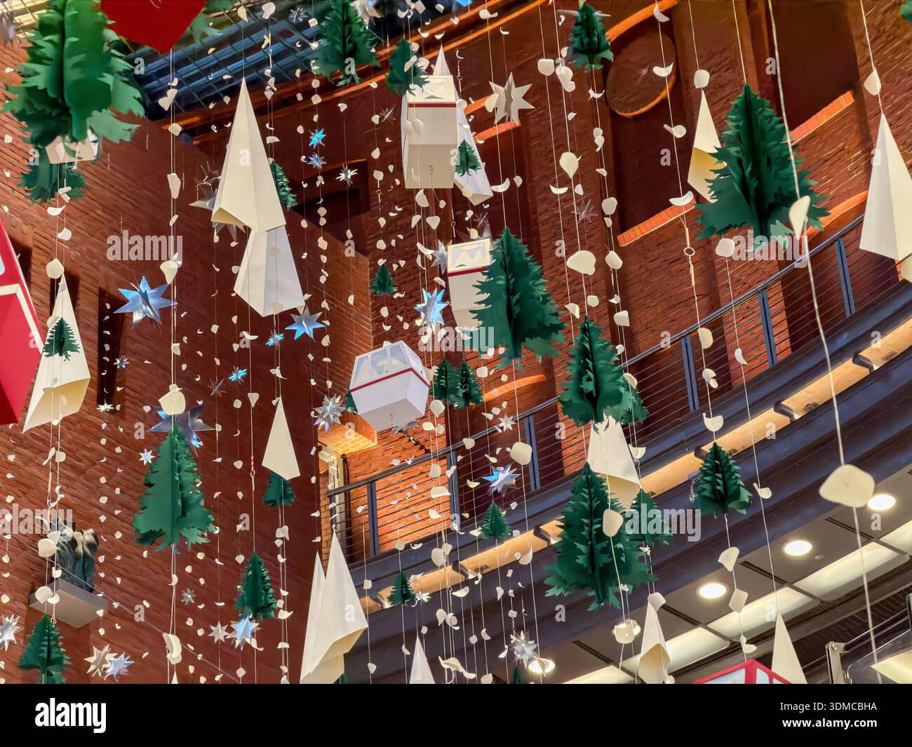 Blick auf die komplexen Weihnachtsbäume aus Papier, leuchtende Sterne und abstrakte weiße Dekorationen, die eine entzückende festliche Präsentation in einem modernen Shopping bilden Stockfoto
