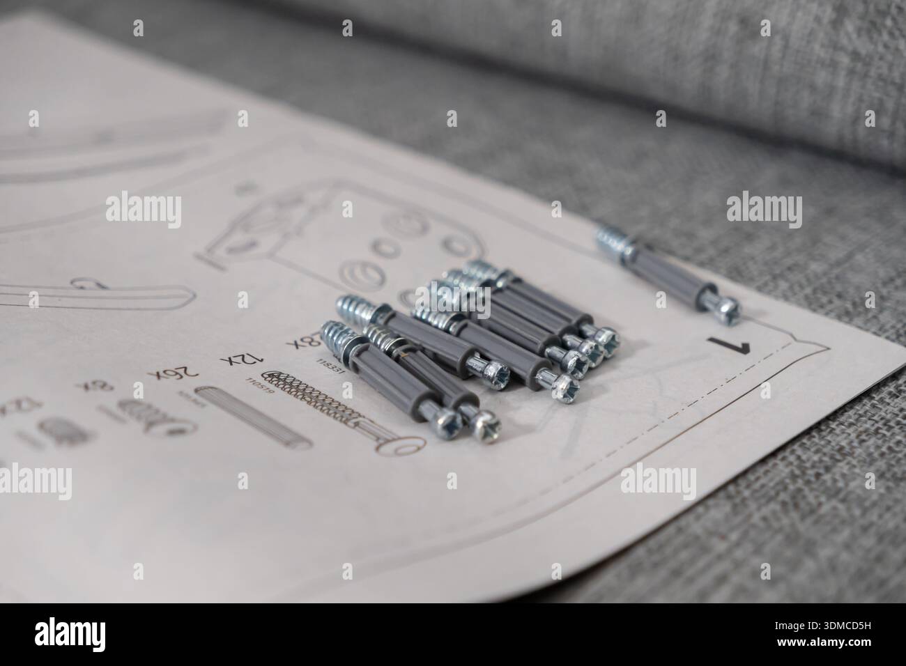 Nahaufnahme neuer Möbelverbinder und Befestigungselemente auf einer gedruckten Montageanleitung, die die Anfangsphase einer Heimwerkereinrichtung oder o verdeutlicht Stockfoto