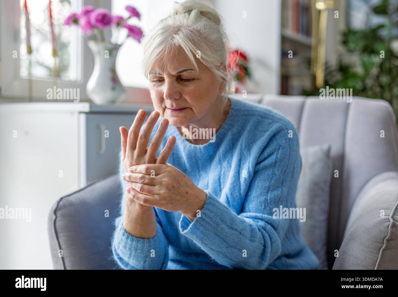 Eine ältere Frau massiert ihre schmerzende Hand Stockfoto