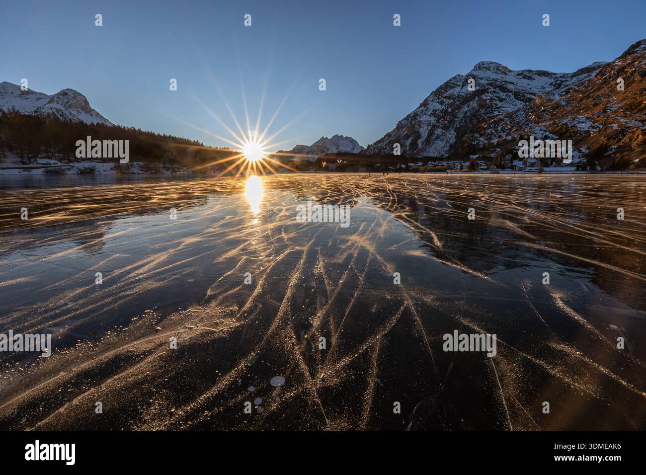 Sonnenuntergang mit Sonnenaufgang über dem gefrorenen See Sils und verwandelt Eislaufbahnen in goldene Linien Stockfoto