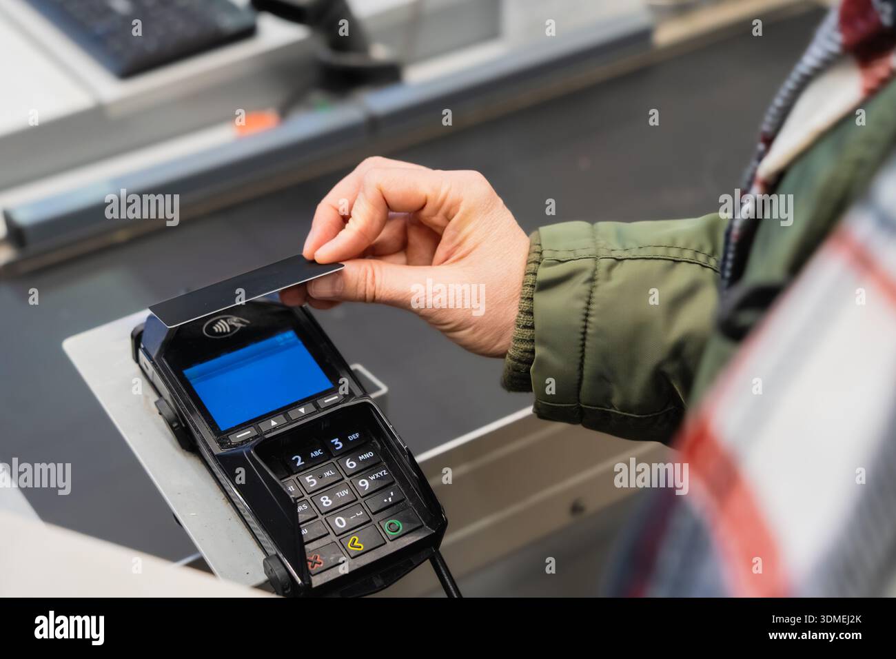Die Person führt eine kontaktlose Zahlungstransaktion an der Kasse durch, was die Benutzerfreundlichkeit moderner Finanztechnologie und Verbraucher unterstreicht Stockfoto