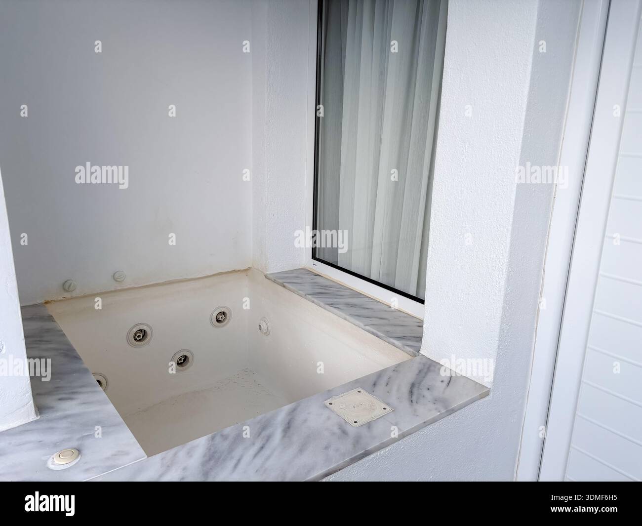 Eingebauter Whirlpool/Whirlpool. Whirlpool-Badewanne, Whirlpool. Weiße Inneneinrichtung mit grauer Marmorumrandung, typisch für die Hotelunterkunft auf Santorin. Stockfoto