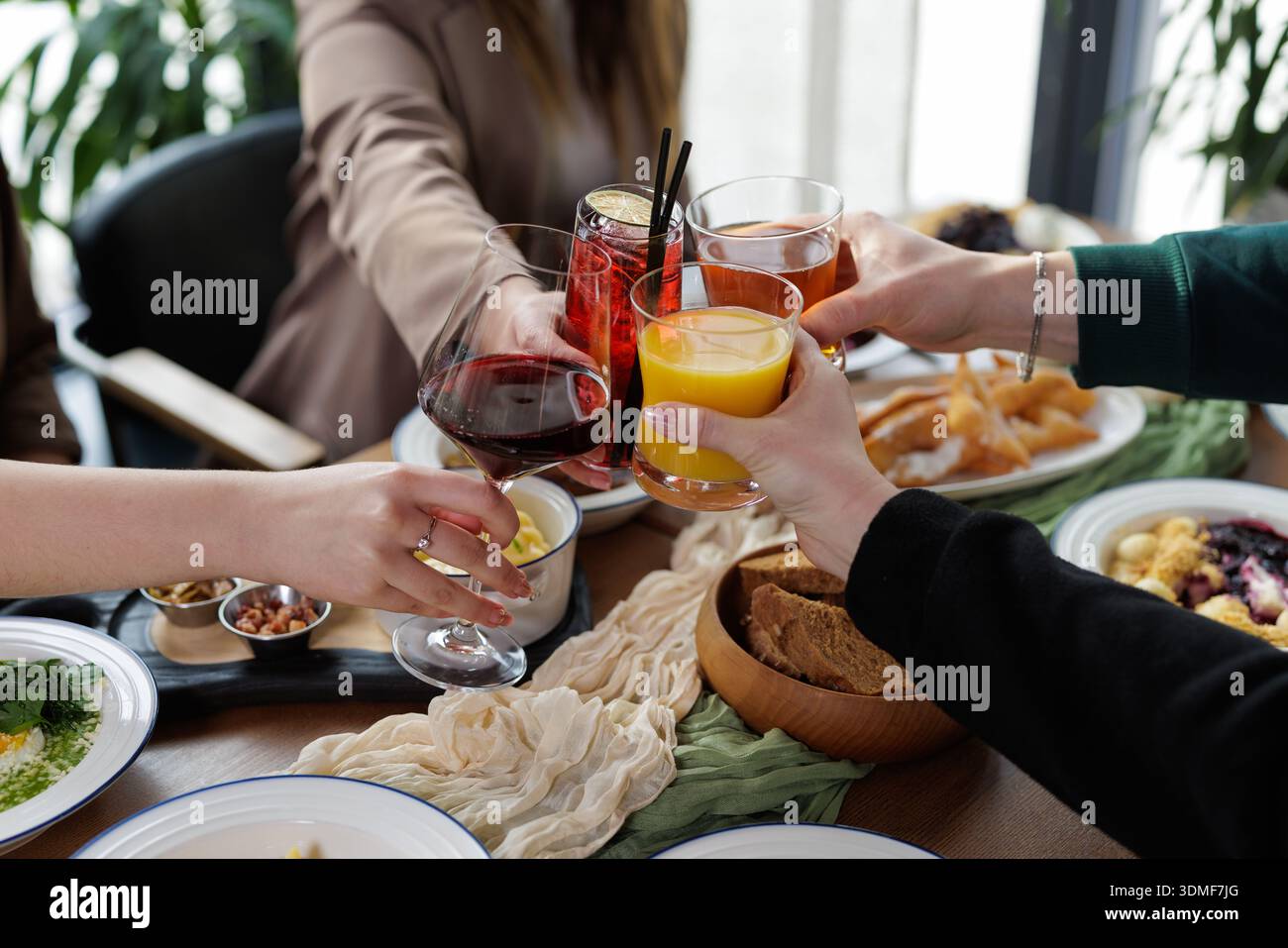 Gruppe von Personen, die bei einer gemeinsamen Mahlzeit Wein, Saft und Cocktails trinken. Ideal für Gastgewerbe, sozialen Lebensstil und Marketing-Visuals für Feiern. Stockfoto