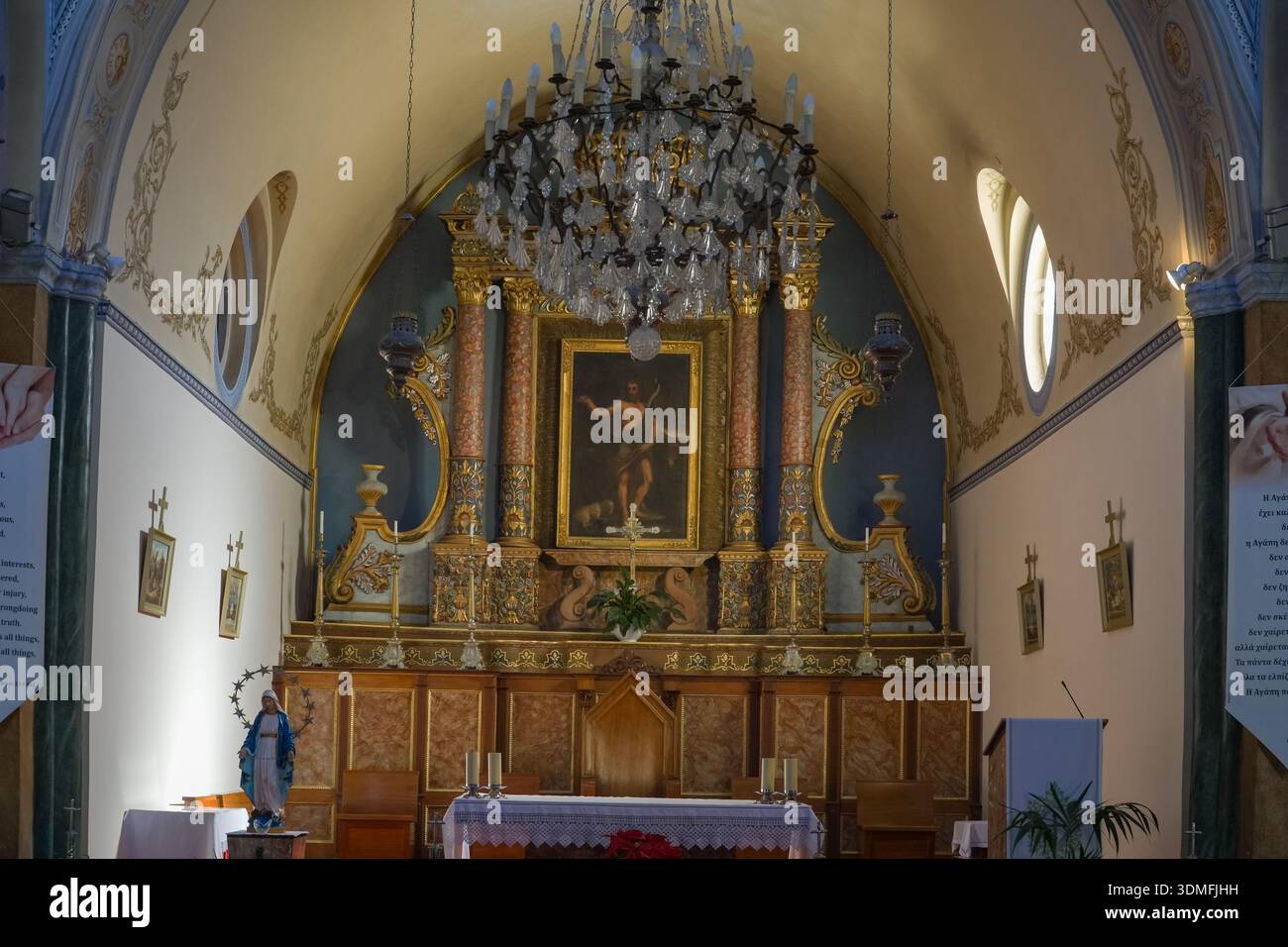 Heilige Kathedrale des Heiligen Johannes des Täufers, katholisches Kircheninnere in Fira, Santorin, Griechenland. Verfügt über einen kunstvollen Retablo-Altar und Kronleuchter. Stockfoto
