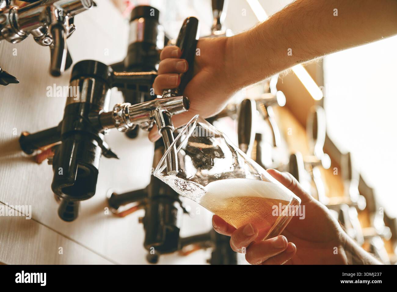 Goldenes Getränk aus dem Tap in Glass in lebendiger Bar-Atmosphäre Stockfoto