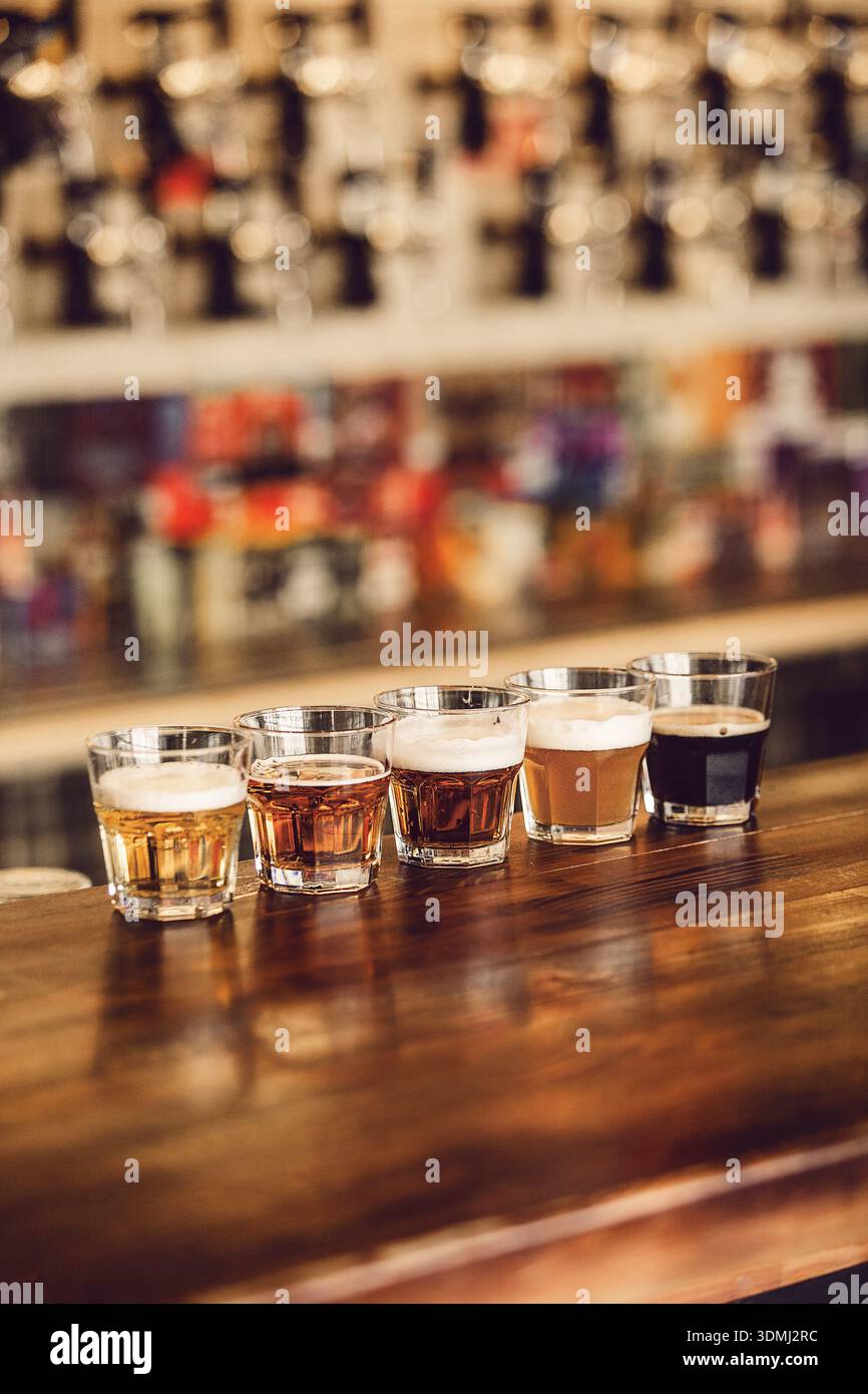 Verschiedene Craft-Biere werden im Verkostungsset am Holztheken der Brauerei präsentiert Stockfoto