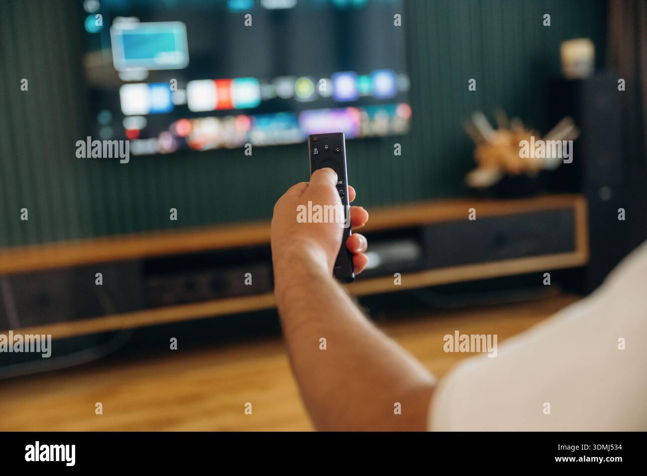 Fokussiertes Foto von der Hand des Mannes, die die Fernbedienung hält, sitzend und in freier Zeit. Stockfoto