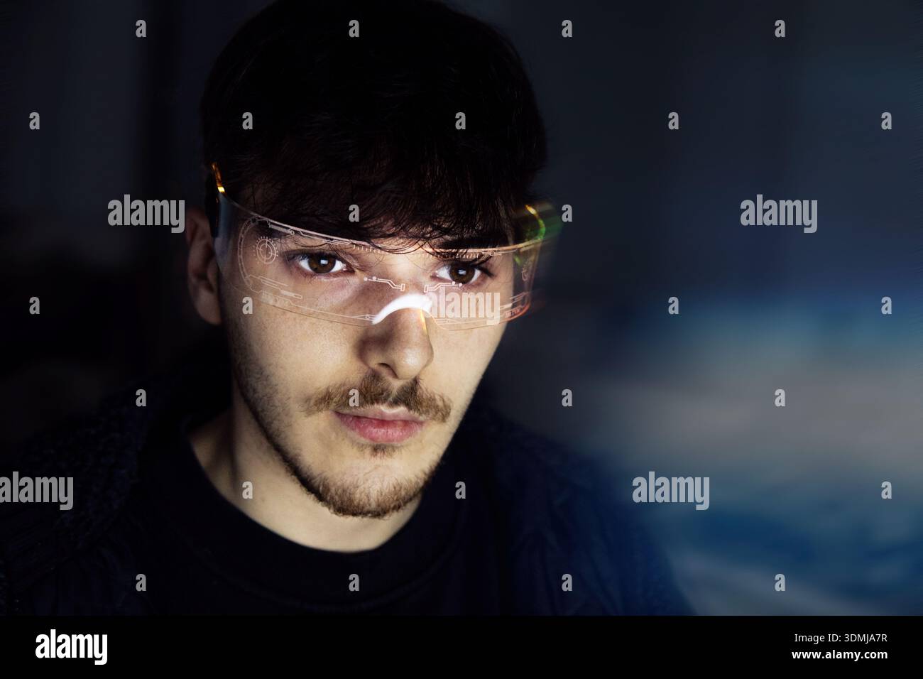 Junger Mann, der Computer mit einer Cyber-Brille benutzt Stockfoto