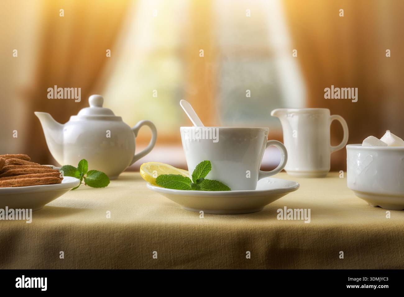 Frisch servierter Pfefferminz- und Zitronentee auf einem Tisch mit brauner Tischdecke und Keramikgläsern mit Keksen im Teeraum. Vorderansicht. Stockfoto