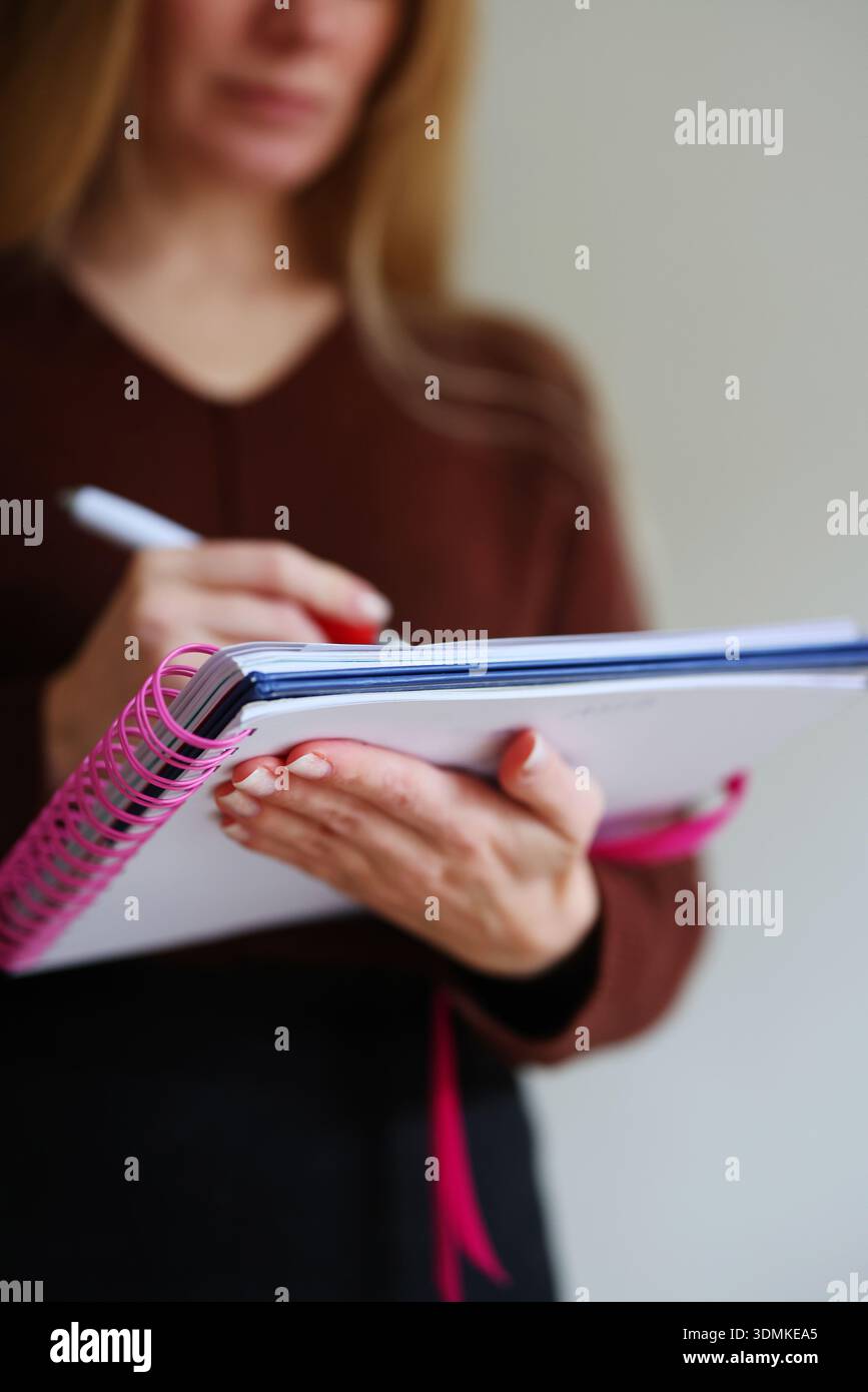 Frau schreibt Notizen in Spiralheft. Nahaufnahme der Hände mit Stift, Planung und Produktivitätskonzept. Stockfoto