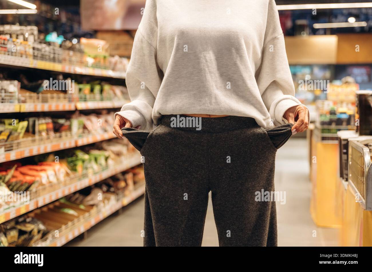 Frau steht im Supermarkt mit leeren Taschen, ohne Geld, Arm. Stockfoto