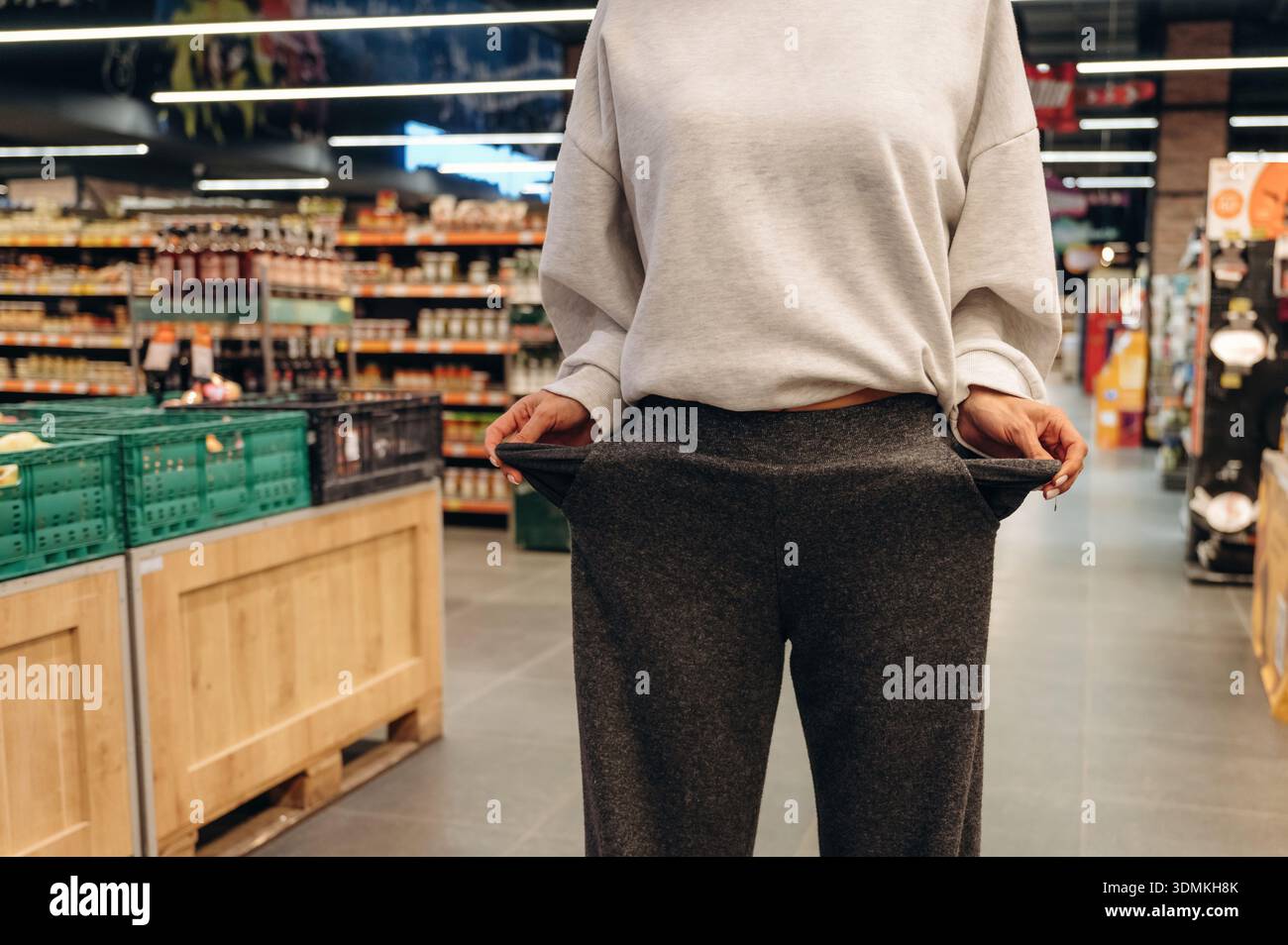 Frau steht im Supermarkt mit leeren Taschen, ohne Geld, Arm. Stockfoto