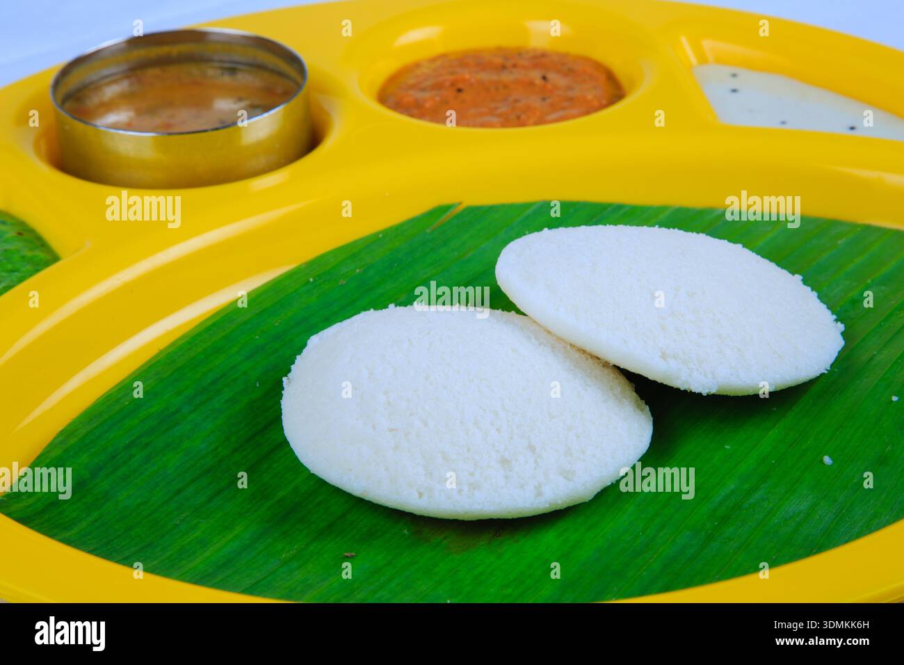 Südindisches Idli serviert auf Bananenblatt mit Chutney und Sambar auf traditionellem Teller Stockfoto