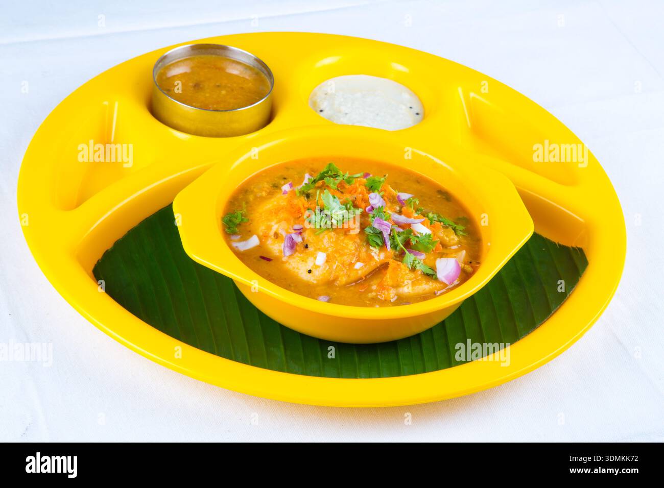 Südindisches Sambar Idli serviert in Schüssel mit Chutney auf Bananenblatt traditionelles Frühstück, südindisches Sambar Idli serviert auf einem modernen gelben Teller Stockfoto