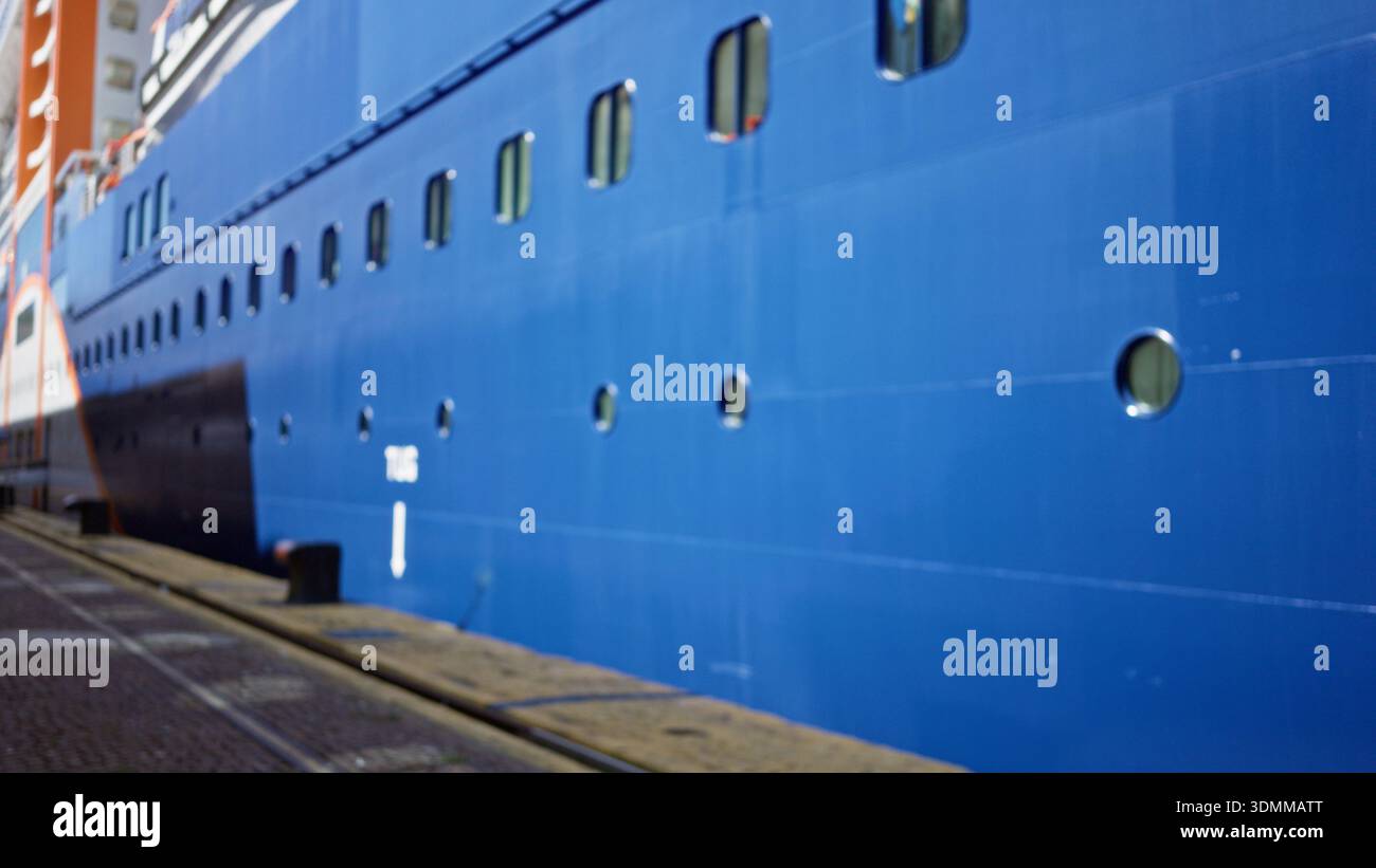 Blauer Schiffsrumpf mit runden Bullaugen und lackierten Metallpaneelen, defokussiert und weich verschwommen im Freien; Hintergrund im Copyspace ruhig. Stockfoto