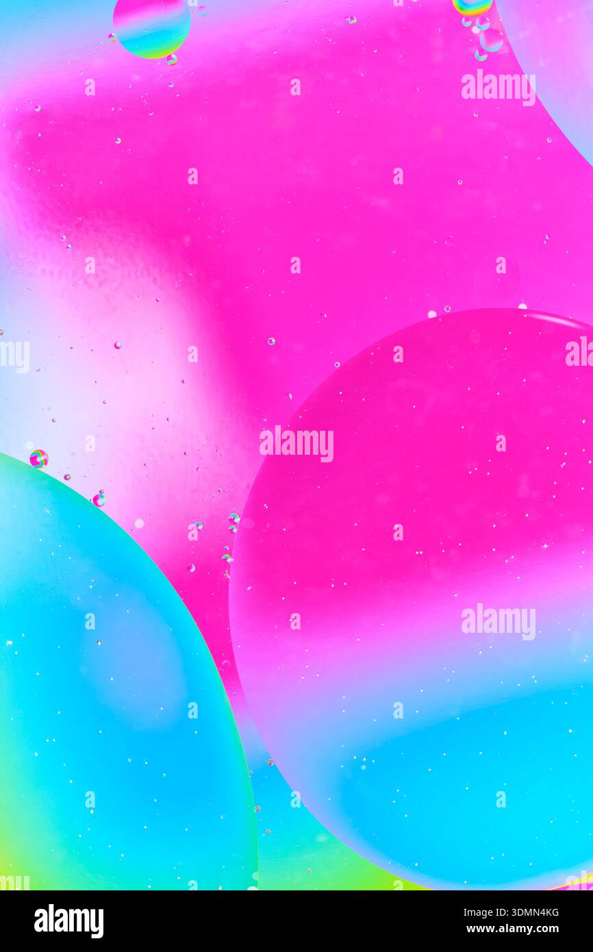 Diagonale Zusammensetzung grosser rosa und blaugrüner Tropfen. Winzige Blasen erzeugen einen Sternenhimmel oder einen mikroskopischen Welteffekt Stockfoto