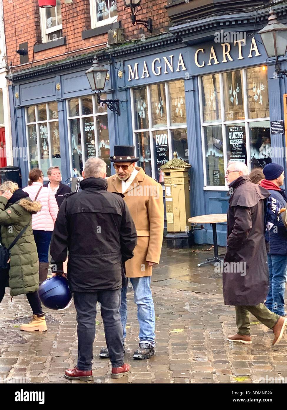 In Lincoln versammeln sich die Mitglieder der Gemeinschaft mit Eisskulpturen und den Burgmauern und den Bürgermeistern, die sich im Straßenmann mit einem Hut über alte Gebäude unterhalten - Smartphone-aufgenommenes Stockfoto