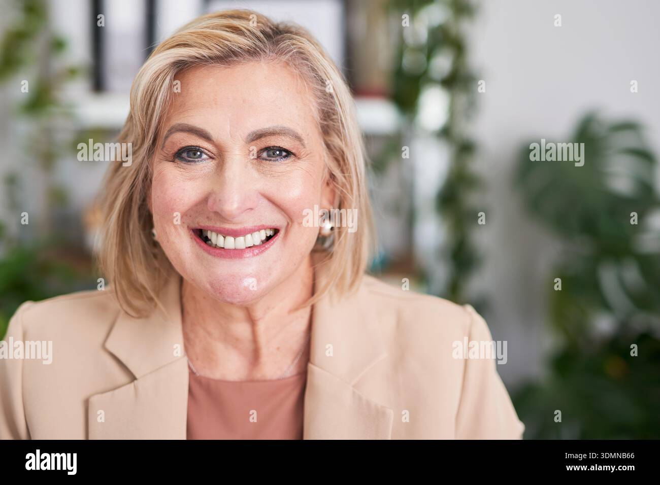 Selbstbewusste professionelle Frau lächelt in Beige Blazer – Büroporträt für Unternehmen und Führung Stockfoto